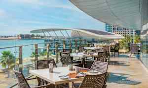 Ulkoravintola, jossa katetut pöydät ja merinäköala. (Tekoälyn luoma teksti)