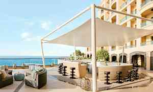 Ulkobaari, jossa on istuma-alue, aurinkovarjo ja näkymä merelle. (Tekoälyn luoma teksti)