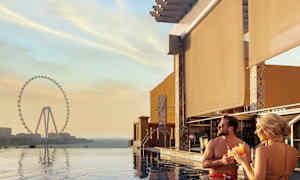 Henkilöt seisovat altaassa ja näköalassa suuri maailmanpyörä auringonlaskun aikaan. (Tekoälyn luoma teksti)