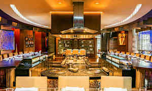 Ravintolan sisätilat, jossa avokeittiö ja ympärillä istumapaikkoja. (Tekoälyn luoma teksti)