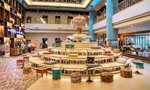 Hotellin sisätila, jossa kirjahylly ympyränmuotoisen istuinalustan ympärillä sekä koristeellinen tunnelma. (Tekoälyn luoma teksti)