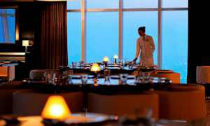 Ravintola, jossa on tyylikkäästi katetut pöydät ja suuret ikkunat näkymällä. (Tekoälyn luoma teksti)