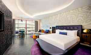 Modernisti sisustettu hotellihuone, jossa suuri sänky ja oleskelualue. (Tekoälyn luoma teksti)