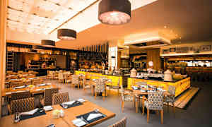 Ravintola, jossa on moderni sisustus, istuinalueet ja avoin keittiö. (Tekoälyn luoma teksti)