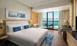 Hotellihuone, jossa on parivuode, istuinryhmä ja parveke merinäköalalla. (Tekoälyn luoma teksti)