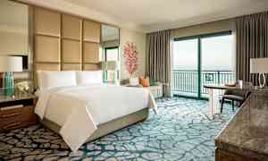 Ylellinen hotellihuone, jossa on parivuode, istuma-alue ja merinäköala. (Tekoälyn luoma teksti)