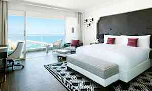 Valoisa ja moderni hotellihuone, jossa on suuri parisänky ja pääsy parvekkeelle merinäköalalla. (Tekoälyn luoma teksti)