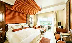 Moderni ja valoisa hotellihuone, jossa on suuri sänky, istuma-alue ja kalustettu parveke merinäköalalla. (Tekoälyn luoma teksti)