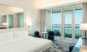 Hotellihuone, jossa vuode, nykyaikainen sisustus ja parveke merinäköalalla. (Tekoälyn luoma teksti)