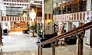 Hotellin aulatila, jossa marmolattia, vastaanottotiski taustalla ja istuinryhmiä. (Tekoälyn luoma teksti)