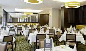 Tyylikäs ravintola, jossa on valkoiset pöytäliinat ja kattaus. (Tekoälyn luoma teksti)