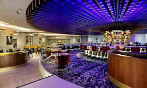 Moderni baari, jossa on värikkäitä kattovalaisimia ja pyöreä baaritiski. (Tekoälyn luoma teksti)