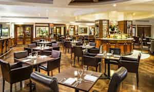 Tyylikäs ravintola, jossa pöydät ja tuolit ovat valmiina aterialle. (Tekoälyn luoma teksti)