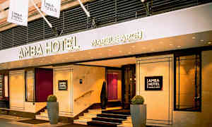 Amba Hotel Marble Arch -hotellin sisäänkäynti, jossa kyltit ja liput. (Tekoälyn luoma teksti)