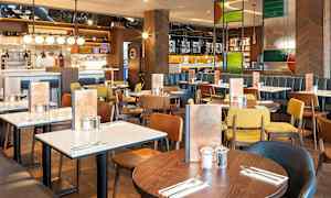 Ravintola, jossa on useita ruokapöytiä ja erivärisiä tuoleja. (Tekoälyn luoma teksti)