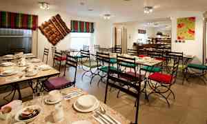 Kahvila, jossa on katettuja pöytiä ja tuoleja värikkäillä tyynyillä. (Tekoälyn luoma teksti)