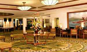 Tyylikkäässä hotellin aulassa on koristeelliset matot, keskellä kukka-asetelma ja mukavat istuimet. (Tekoälyn luoma teksti)