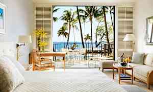 Hotellihuone, jossa on vaalea sisustus, vuode, oleskelutila ja parveke näkymällä merelle ja palmupuihin. (Tekoälyn luoma teksti)