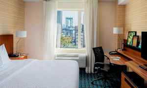 Hotellihuone, jossa on sänky, työpöytä ja ikkuna. Ikkunasta näkyy silta. (Tekoälyn luoma teksti)