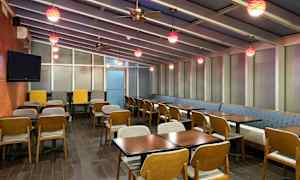 Ravintolatila, jossa on kattoikkuna, pöytiä ja tuoleja sekä värikkäitä riippuvaloja. (Tekoälyn luoma teksti)