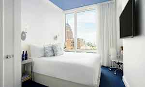 Kuva hotellihuoneesta, jossa on mukava parivuode, iso ikkuna ja moderni sisustus. (Tekoälyn luoma teksti)