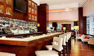 Elegantin baarin sisustus, jossa on hyvin varusteltu baaritiski ja valkoiset baarituolit. (Tekoälyn luoma teksti)