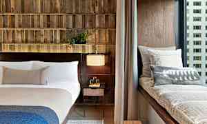 Moderni makuuhuone, jossa on sänky, ikkunarahi tyynyllä ja yöpöytälamppu. (Tekoälyn luoma teksti)