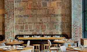 Huone, jossa on tiiliseinät ja puupöydät, järjestetty ravintolakäyttöön. (Tekoälyn luoma teksti)