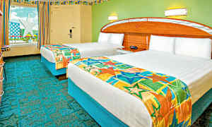 Hotellihuone, jossa on kaksi yksittäistä sänkyä, jotka on peitetty värikkäillä päiväpeitteillä. Seinät on maalattu vihreiksi, ja ikkunasta on näkymä tähtimuotoiseen rakennelmaan. (Tekoälyn luoma teksti)