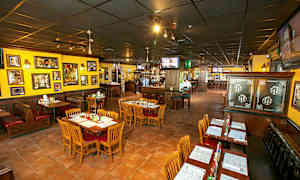 Ravintola, jossa on pöytiä ja tuoleja, värikkäät seinät ja koristeita. (Tekoälyn luoma teksti)