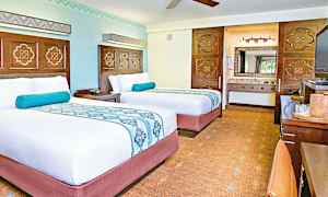 Kaksi siististi pedattua sänkyä hotellihuoneessa, jossa on vaaleat seinät ja koristeellisia yksityiskohtia. (Tekoälyn luoma teksti)