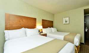 Hotellihuone, jossa kaksi vuodetta, puiset päätylevyt ja lampuja yöpöydillä. (Tekoälyn luoma teksti)