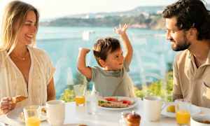 Perhe syö aamiaista pöydän ääressä, josta on näkymä merelle. (Tekoälyn luoma teksti)