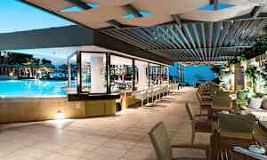 Ulkobaari, jossa tuoleja ja pöytiä valaistun uima-altaan vieressä. (Tekoälyn luoma teksti)