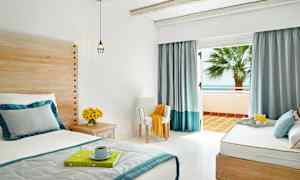 Valoisa makuuhuone, jossa sänky, tuoli ja parveke merinäkymällä. (Tekoälyn luoma teksti)