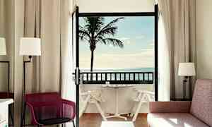 Hotellihuone, jossa on parveke, näköala palmuun ja merelle. (Tekoälyn luoma teksti)
