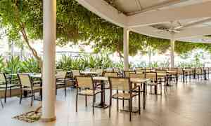 Kuva ulkoilmaravintolasta, jossa on pöytiä ja tuoleja katoksen alla. (Tekoälyn luoma teksti)