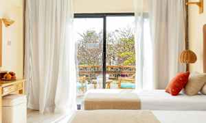 Hotellihuone, jossa on parivuode ja lasiovi, joka johtaa parvekkeelle. (Tekoälyn luoma teksti)