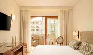 Moderni hotellihuone, jossa parivuode, kirjoituspöytä, televisio ja parveke näkymällä. (Tekoälyn luoma teksti)