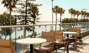 Puisia tuoleja ja pöytiä parvekkeella, näkymä palmuihin ja merelle. (Tekoälyn luoma teksti)