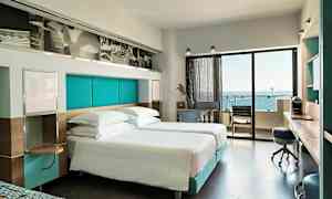 Moderni hotellihuone, jossa parivuoteet ja merinäköala parvekkeelta. (Tekoälyn luoma teksti)