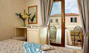 Hotellihuone, josta ikkunan kautta näkymä parvekkeelle, pöytä samppanjan kanssa ja näkymä rakennukseen. (Tekoälyn luoma teksti)