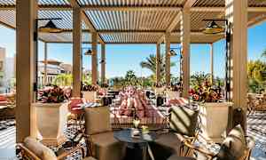 Ulkoa lounge-alue istuimineen ja kasveineen, taustalla aurinkoinen sää. (Tekoälyn luoma teksti)