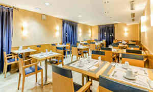 Ruokailuhuone, jossa on asetettu pöytiä ja tuoleja, lämpimän sävyiset seinät ja siniset verhot. (Tekoälyn luoma teksti)