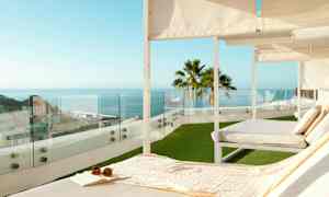 Aurinkotuoleja terassilla, josta on näkymä merelle ja kaupunkiin. (Tekoälyn luoma teksti)