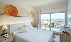 Hotellihuone, jossa on parivuode, koristeellinen taideteos oranssista simpukasta seinällä ja parveke merinäköalalla. (Tekoälyn luoma teksti)