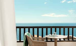 Näköala parvekkeelta, jossa pöytä, tuoli ja merinäkymä. (Tekoälyn luoma teksti)