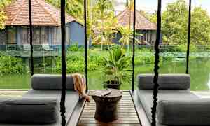 Terassilla riippuvat istuimet, näkymä vehreään puutarhaan ja pieniin ruskeakattoisiin taloihin. (Tekoälyn luoma teksti)