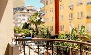 Näkymä parvekkeelta kadulle, jota ympäröivät rakennukset ja vehreys. (Tekoälyn luoma teksti)