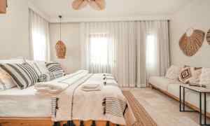 Vaalea ja tyylikäs makuuhuone, jossa on parivuode, koristeellisia tyynyjä ja tekstiilejä. (Tekoälyn luoma teksti)